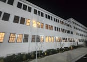 Thumbnail 15 of 53 - A white building with windows lit up at night.