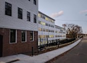 Thumbnail 6 of 53 - A long white building with a black fence in front of it.