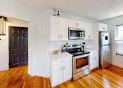 Thumbnail 1 of 24 - A kitchen with white cabinets and a wooden floor.