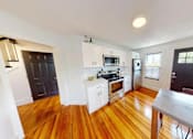 Thumbnail 2 of 24 - A kitchen with wooden floors and white walls.
