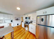 Thumbnail 6 of 24 - A kitchen with wooden floors and stainless steel appliances.