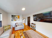 Thumbnail 9 of 24 - A living room with a grey couch and a brown rug.