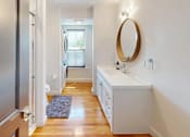 Thumbnail 21 of 24 - A bathroom with a white vanity and a round mirror.