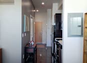 Thumbnail 6 of 12 - A hallway with a door on the right and a plant on the left.