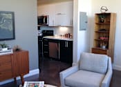 Thumbnail 4 of 12 - A grey chair is in the foreground of a kitchen.