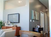 Thumbnail 2 of 12 - A living room with a grey couch and a wooden table.