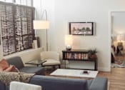 Thumbnail 10 of 12 - A living room with a grey couch and a painting on the wall.