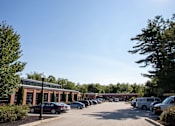 Thumbnail 5 of 12 - A parking lot with cars and a building in the background.