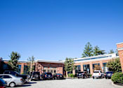 Thumbnail 9 of 12 - A parking lot with cars and a building in the background.