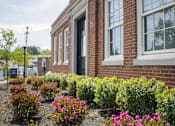Thumbnail 6 of 12 - A red brick building with a flower bed in front.