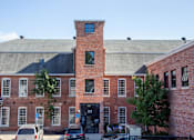 Thumbnail 1 of 12 - A red brick building with a black door and a black fence.