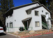 Thumbnail 4 of 18 - A white house with a green door and a sign on the front.