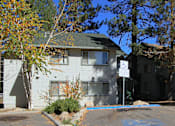Thumbnail 2 of 18 - A white building with a green roof is surrounded by trees.
