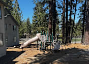 Thumbnail 14 of 18 - A playground with a slide and swings in a residential area.