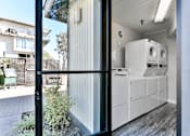 Thumbnail 19 of 19 - A modern kitchen with white appliances and a black door.