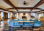 Thumbnail 16 of 24 - A large blue couch sits in the middle of a spacious room with a brick fireplace at The Meadows Apartments, Culver City , CA 90230