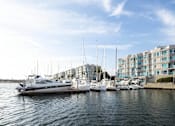 Thumbnail 8 of 8 - A yacht is docked at a marina with other boats and a building in the background.