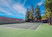 Thumbnail 14 of 17 - A tennis court surrounded by a fence and trees at Valley Plaza Villages, California, 94566