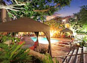 Thumbnail 1 of 10 - A poolside area with a tent and chairs is lit up at night.