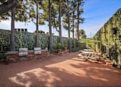 Thumbnail 13 of 13 - A patio with a table and chairs surrounded by a wall of green plants at Villa Vicente, Los Angeles, CA