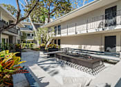 Thumbnail 12 of 13 - A patio with a table and chairs is surrounded by buildings at Villa Vicente, Los Angeles, CA