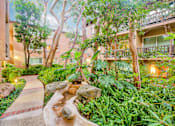 Thumbnail 21 of 23 - a garden with trees and rocks and a stream at Casa Granada, Los Angeles, 90049