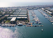 Thumbnail 6 of 19 - A marina with boats docked and a building in the background.