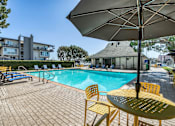 Thumbnail 10 of 19 - A sunny day at the pool with a yellow umbrella and chairs.