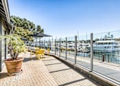 Thumbnail 13 of 19 - A patio with a table and chairs overlooking a marina.