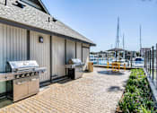 Thumbnail 16 of 19 - A barbecue grill is on a wooden deck next to a building.