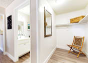 Thumbnail 11 of 16 - A white bathroom with a wooden chair and a mirror.
