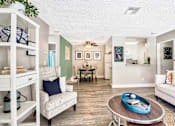 Thumbnail 6 of 16 - A living room with a white couch, a coffee table, and a dining table.