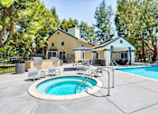 Thumbnail 5 of 16 - A pool with a hot tub and a house in the background.