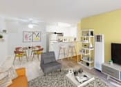 Thumbnail 8 of 18 - A living room with a grey sofa, a white coffee table, and a yellow accent wall at West Park Village, Los Angeles, CA