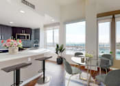 Thumbnail 11 of 34 - A modern kitchen with a bar area and a dining table set up at Esprit Marina del Rey, 90292