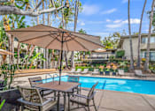 Thumbnail 7 of 15 - A patio with a table and chairs under an umbrella next to a pool.