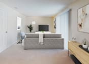Thumbnail 4 of 12 - A person is sitting on a chair in a room with a grey couch and a television.