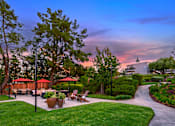 Thumbnail 2 of 13 - A beautiful outdoor seating area with tables and chairs surrounded by greenery and trees.