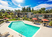 Thumbnail 5 of 13 - A swimming pool surrounded by lounge chairs and umbrellas in a residential area.