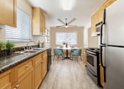 Thumbnail 4 of 12 - A kitchen with wooden cabinets and a black refrigerator at Pleasanton Place, Pleasanton, CA, 94566
