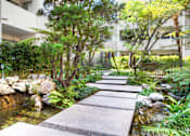 Thumbnail 1 of 14 - A garden with a stone pathway leading to a pond.