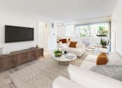 Thumbnail 7 of 14 - A living room with a white couch, a coffee table, and a flat screen TV.