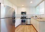 Thumbnail 9 of 14 - A modern kitchen with a stainless steel refrigerator and white cabinets.