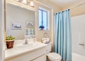 Thumbnail 10 of 16 - A bathroom with a white sink, toilet, and blue shower curtain.