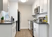 Thumbnail 6 of 17 - A kitchen with white cabinets and black countertops at Valley Plaza Villages, California, 94566