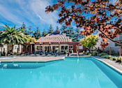 Thumbnail 13 of 17 - A swimming pool surrounded by trees and a building with a red roof at Valley Plaza Villages, California, 94566