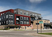 Thumbnail 2 of 19 - A multi-story building with a red and black exterior.