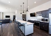 Thumbnail 11 of 19 - A modern kitchen with dark wood floors and stainless steel appliances.