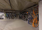 Thumbnail 7 of 19 - A car is parked in a garage with a wall of bicycles.