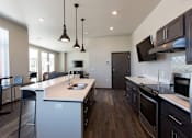 Thumbnail 10 of 19 - A modern kitchen with dark wood floors and a white island.
